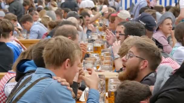 17 Eylül 2017 - Oktoberfest, Münih, Almanya: birçok insan bira kupalar iletişim ve eğlenin bira içme birgarten içinde oturuyor — Stok video