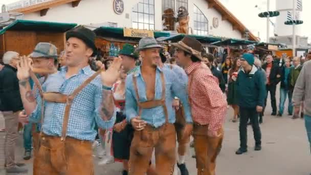 17 de setembro de 2017 - Oktoberfest, Munique, Alemanha: alegre companhia de jovens em ternos nacionais bávaros Lederhose e camisetas quadriculadas coloridas para se divertir em Theresienwiese — Vídeo de Stock