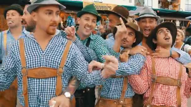 September 17, 2017 - Oktoberfest, München, Tyskland: Glada sällskap av unga i nationella bayerska kostymer Lederhose och färgglada rutiga skjortor att ha kul på Theresienwiese — Stockvideo