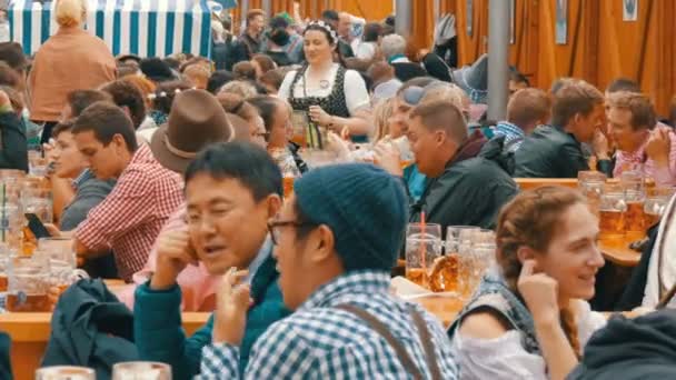 17. September 2017 - Oktoberfest, München, Deutschland: Menschen sitzen auf der Theresienwiese in Bayern beim Weltbierfest und trinken Bier aus riesigen Glasbechern — Stockvideo
