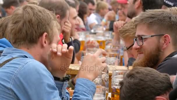 17 de setembro de 2017 Oktoberfest, Munique, Alemanha: Muitas pessoas estão sentadas no birgarten bebendo cerveja de canecas de cerveja se comunicam e se divertem — Vídeo de Stock
