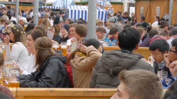 17 сентября 2017 - Октоберфест, Мюнхен, Германия: Много людей сидят в биргартене и пьют пиво из кружек пива общаются и веселятся — стоковое видео