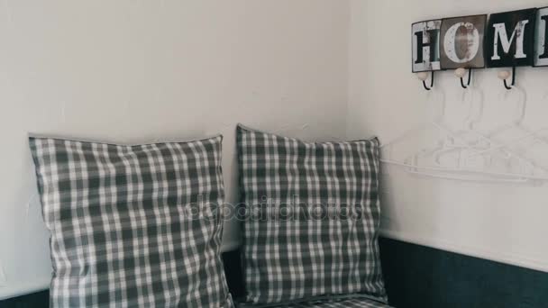 Gezellige hoek met geruite kussens en een leuke stijlvolle kapstok op de muur met de naam van een gezellig huis — Stockvideo