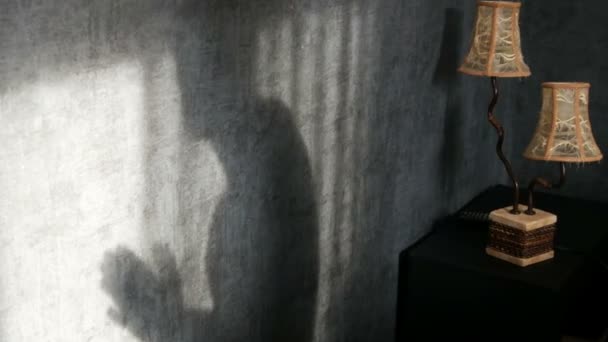 Une ombre menaçante dans une pièce sombre gothique à côté d'une lampe jaune vintage, se frotte les mains avec colère. Fantôme ou sorcière pour Halloween . — Video