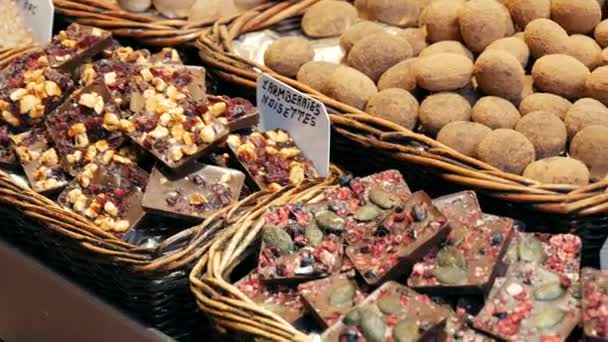 22 września 2017 - Barcelona, Hiszpania, Mercator de la Boqueria rynku żywności: ogromny licznika za pomocą nakrętki słodycze czekoladowe, słodycze, kulki. Chałwa. Słodycze w glazury. Płytki, czarny i czekolada mleczna — Wideo stockowe