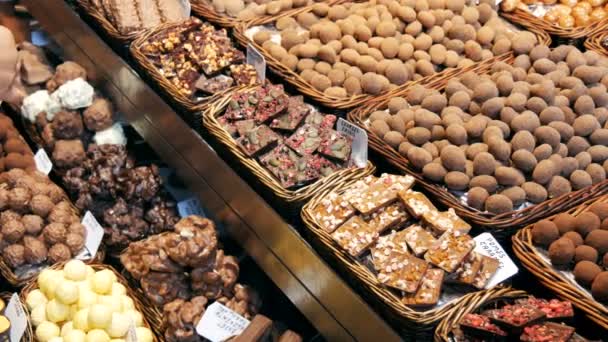 22. september 2017 - barcelona, spanien, mercator de la boqueria food market: eine riesige theke mit süßen schokoladennüssen, bonbons, bällchen. Halva. Süßigkeiten in der Glasur. Fliesen aus schwarzer und Vollmilchschokolade — Stockvideo