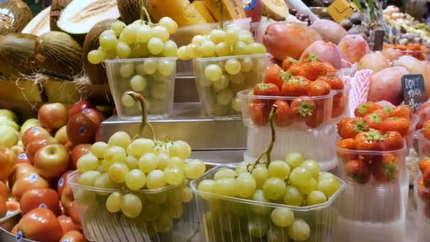 September 22, 2017 - Barcelona, Spain, Mercator de la Boqueria Food Market: a huge counter with tropical fruits, mango, grapes, kiwi, bananas.People choose fruit in bazaar or in Fruit Market — стоковое видео