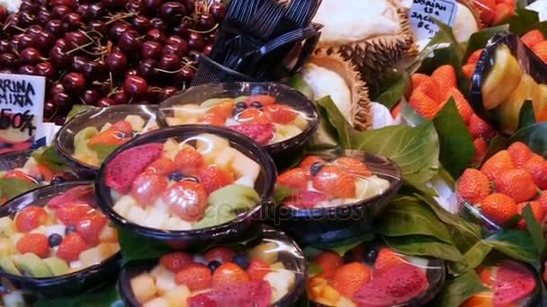 Mélange de différents fruits à la fraise mangue kiwi pitaia et d'autres dans une assiette en plastique sur le comptoir du marché aux fruits à Barcelone, Espagne — Video