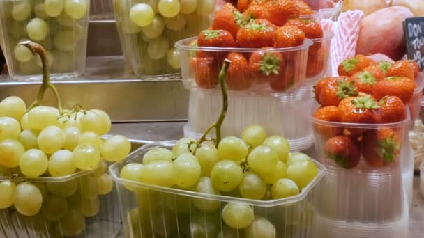 Färska druvor och jordgubbar och tropiska frukter på marknaden racket — Stockvideo
