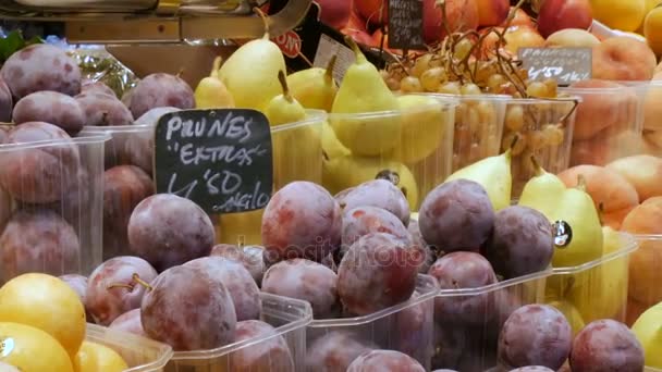 22. september 2017 - barcelona, spanien, mercator de la boqueria lebensmittelmarkt: blaue und gelbe große pflaumen liegen auf der theke in einem fruchtmarkt — Stockvideo