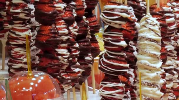 Mistura de frutas diferentes em copos de plástico nas prateleiras e morangos em esmalte de chocolate do mercado de frutas — Vídeo de Stock