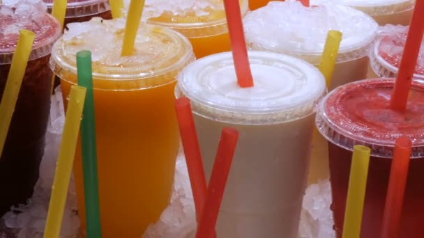 Сок смузи или свежий в пластиковых чашках с цветными соломинками на прилавке фруктового рынка — стоковое видео