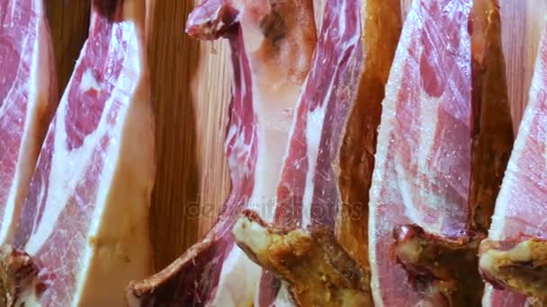 Coxas de porco secas penduradas no balcão do mercado de carne. Prato nacional espanhol de presunto ou jamon com listras de gordura, mercado de La Boqueria, Espanha — Vídeo de Stock
