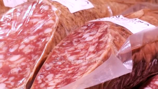 Deliciosas salchichas frescas de salami cuelgan en el mostrador del mercado de carniceros de carne de cerca — Vídeos de Stock