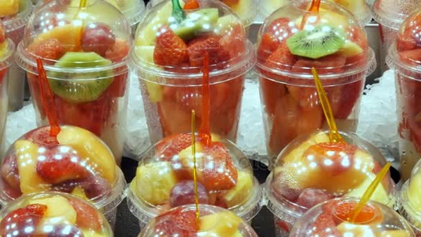 Friss frissen csomagolt gyümölcs görögdinnye, kivi, körte, alma, mangó, gránátalma, eper, amelyben a forks megragadt közel fel a műanyag pohár-mix — Stock videók