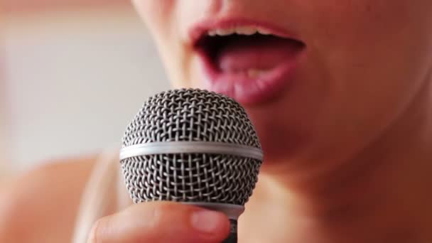 Beautiful young girl speaks in vocal, hand-held dynamic microphone.Mouth girl in headphones speaks into the microphone in the studio close up — Stock Video