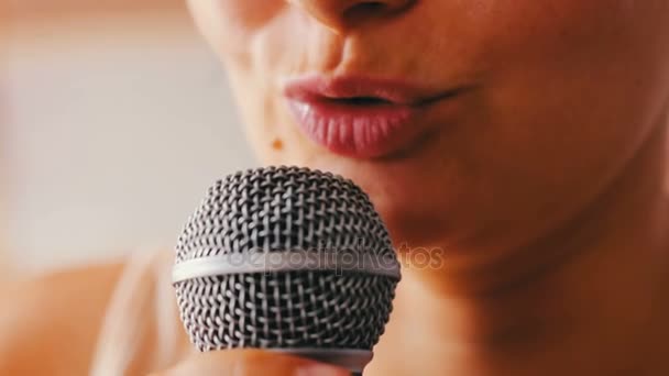 Красивая девушка поет что-то в ручном микрофоне — стоковое видео