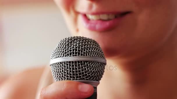 Beautiful girl says something in a hand-held microphone — Stock Video