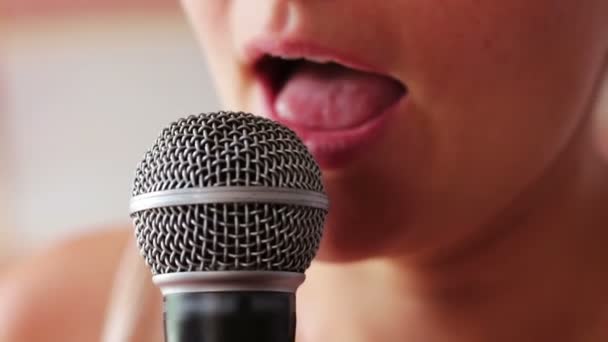 Красивая девушка поет что-то в ручном микрофоне — стоковое видео