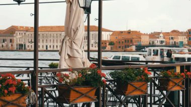 Güzel bir tekne turist ile geçerek tencere içinde belgili tanımlık geçmiş Venedik'te bir büyük kanal dolgu üzerinde kırmızı çiçekler