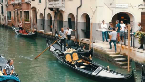 VENICE, ITALY, SEPTEMBER 7, 2017: gondolas dan gondoliers indah dengan wisatawan di atasnya berkendara melalui saluran Venesia tua — Stok Video