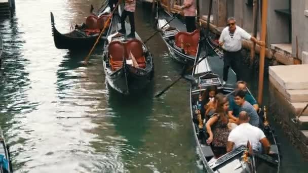 Benátky, Itálie, 7 září 2017: Krásné gondoly a gondoliéři s turisty na nich projet starých benátských kanálů — Stock video