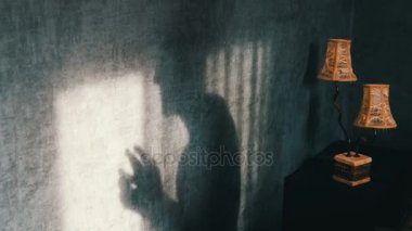 Korkunç gölge uğursuzca parmak bir vintage sarı lamba yanındaki Gotik karanlık bir odada. Bir hayalet ya da bir cadı Cadılar Bayramı için.