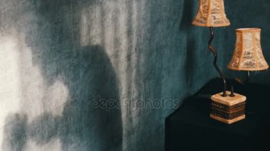 Kurabiye yemek ve bir kupa çay içme bir vintage sarı lamba yanındaki Gotik karanlık odada kamburlu korkunç gölge. Bir hayalet ya da bir cadı Cadılar Bayramı için.