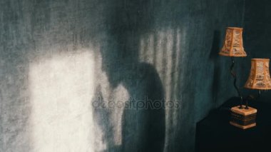 Kurabiye yemek ve bir kupa çay içme bir vintage sarı lamba yanındaki Gotik karanlık odada kamburlu korkunç gölge. Bir hayalet ya da bir cadı Cadılar Bayramı için.