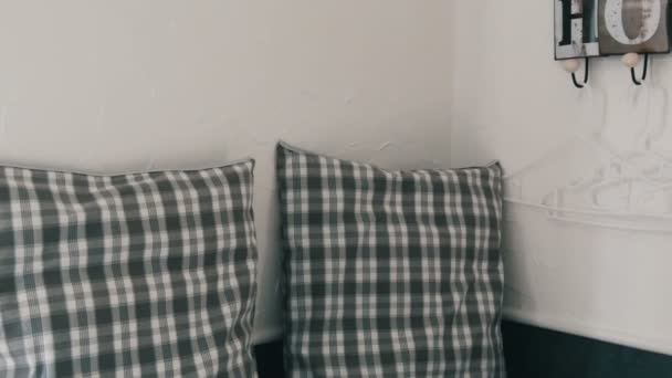 Уютный уголок с клетчатыми подушками и симпатичной стильной вешалкой для пальто на стене с уютным названием дома — стоковое видео