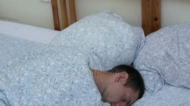 Молодой человек сладко спит в постели в позе эмбриона с бокового вида сверху. — стоковое видео