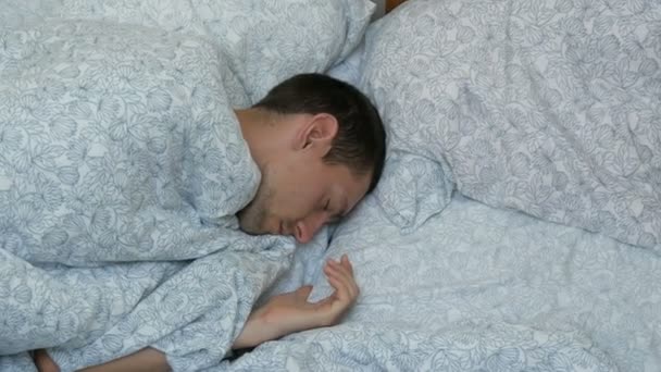Ember alszik az ágyban, felülnézet. Fiatal aranyos srác nyugszik egy párnát. Zár-megjelöl szemcsésedik-ból fiatal férfi az ágyban otthon alszik. — Stock videók