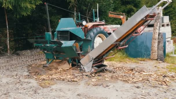 Petite scierie du village. Un tracteur et un support de scie dans les bois, le long des troncs coupés et emballés — Video