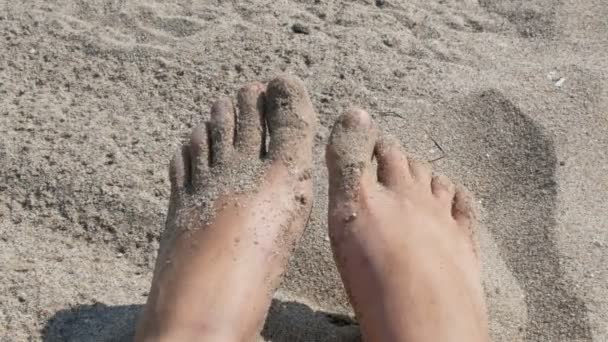 Женские загорелые ноги и пальцы двигаются на фоне песка на пляже — стоковое видео