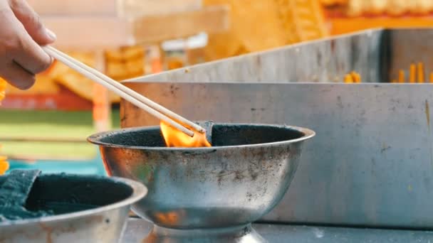 People light scented wands of good luck and wax candles from bowl of living fire. Buddhist religion. — Stock Video