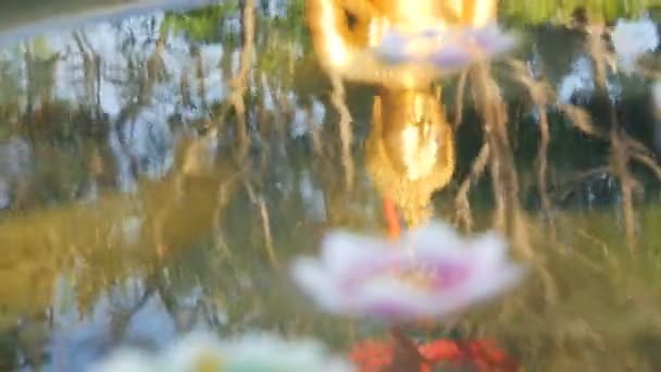 Gyönyörű golden visszaverődés a Buddha szobor, a víz, amely különböző viasz gyertyát úszó lotus formájában