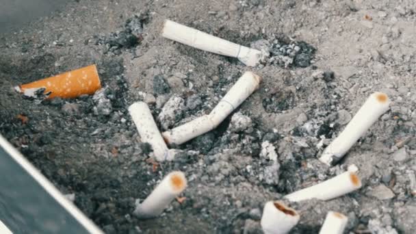 Desplazamiento de la cacerola de colillas de cigarrillos en el cenicero, cenicero con cigarrillo para fumar, herramientas para fumadores pesados, cenicero con vistas colillas — Vídeos de Stock