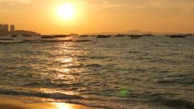 Dağların fon karşı sahilde doğal kırmızı günbatımı. Denizin dalgaları kıyıya akşam yendi. Denizin üzerinde zevk tekneler