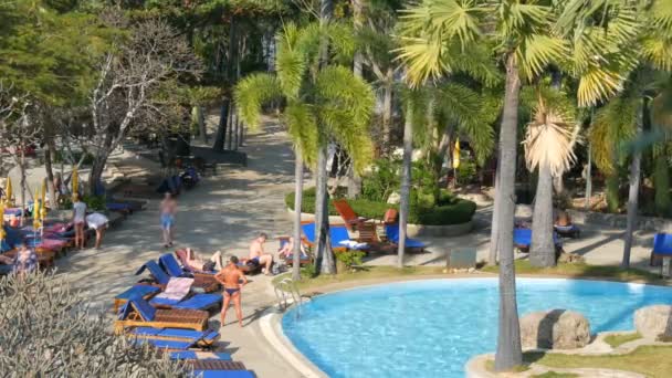 PATTAYA, TAILANDIA - 25 DE DICIEMBRE DE 2017: La gente se relaja en las tumbonas, tomando el sol bajo el sol cerca de la piscina — Vídeos de Stock