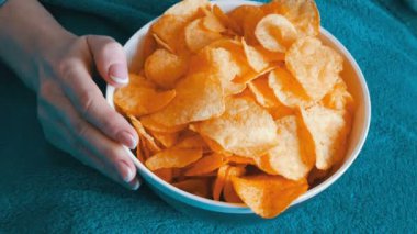 Büyük tabak patates cipsi ile. Kadın kanepede yatıyor ve patates cipsi, yemek görünümü kapatın