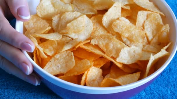 Schöne gepflegte Frauenhände mit französischer Maniküre essen Kartoffelchips von einem riesigen Teller auf der Couch — Stockvideo