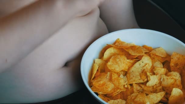 두꺼운 소년 소년 감자 칩을 먹고입니다. 아이의 복 부에 지방의 폴드입니다. 건강에 해로운 음식, 패스트 푸드 — 비디오