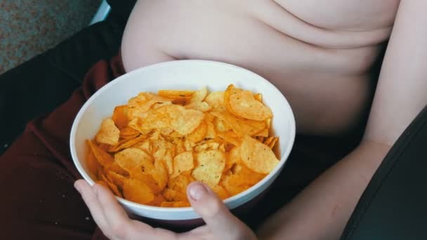 Fet tonåring med fett veck på sin kropp är att äta potatischips. Ohälsosam mat, snabbmat. Barnens kost problem — Stockvideo