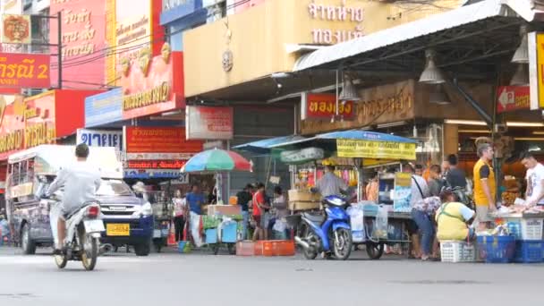 芭堤雅, 泰国-2018年2月7日: 活泼的泰国街有许多红色的迹象。人们卖街头食品。摩托车和汽车经过 — 图库视频影像