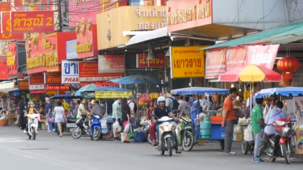 芭堤雅, 泰国-2018年2月7日: 活泼的泰国街有许多红色的迹象。人们卖街头食品。摩托车和汽车经过 — 图库视频影像