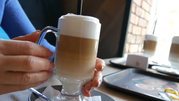 Schöne weibliche Hände, die ein Glas mit Latte im Café halten — Stockvideo