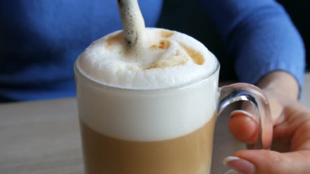 Las manos femeninas están agitando la espuma de aire del café con paja — Vídeos de Stock