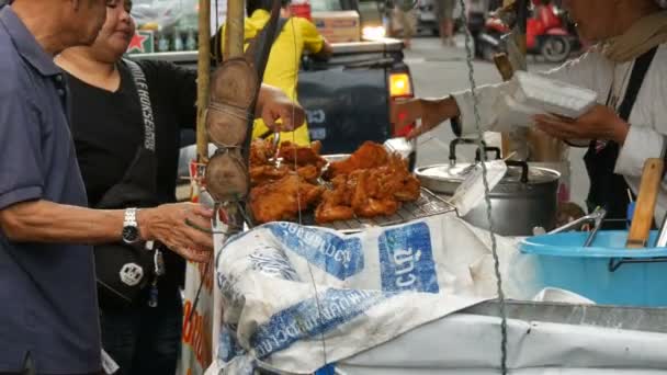 Pattaya, Thailand - 17 December 2017: Vader en zoon kiezen voedsel een straatventer. Straatvoedsel van Thailand. Gebakken stukjes kip in beslag. De verkoper op de straat is de verkoop van een exotische schotel — Stockvideo