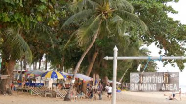 Pattaya, Tayland, 14 Aralık 2017: Palmiye ağaçları ve hindistancevizi Tayland beach Promenade görünümü. İnsanlar sahilde dinlenin. İngilizce kalkan alanında bir yazıt ile bir işaretçi