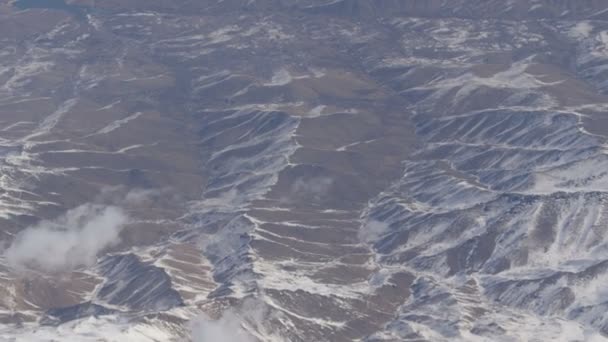 うっすら雪、雲、通り過ぎる飛行機の窓からの眺めと美しい山の範囲 — ストック動画